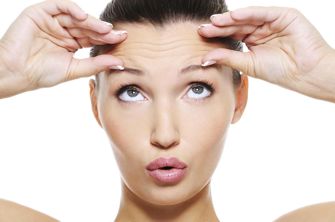 mujer tocandose arrugas de expresion en la frente